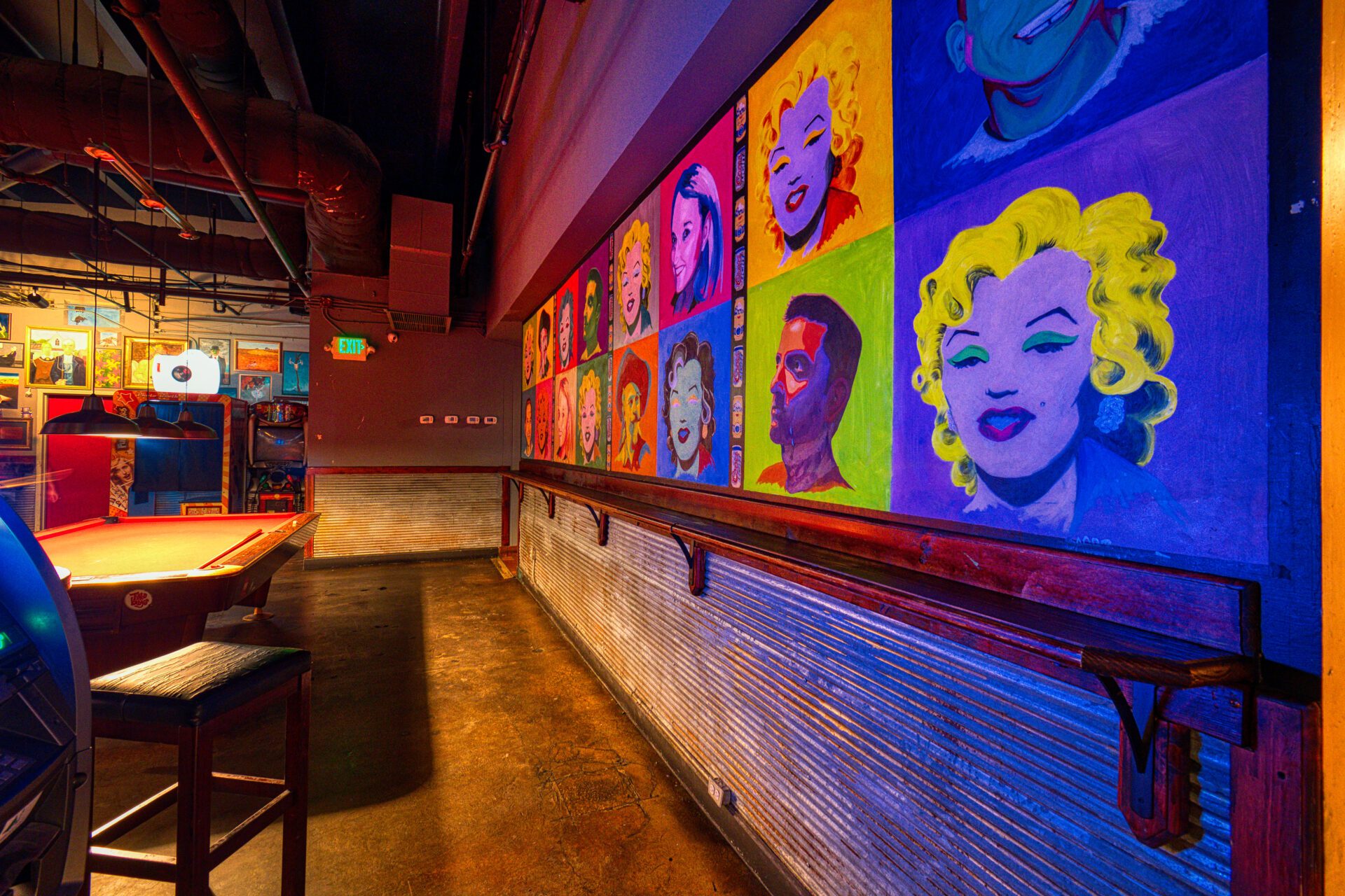 wide wall of colorful pop art and bar table and stools