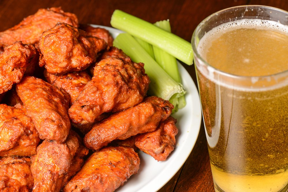 plate of buffalo wings beer and celery